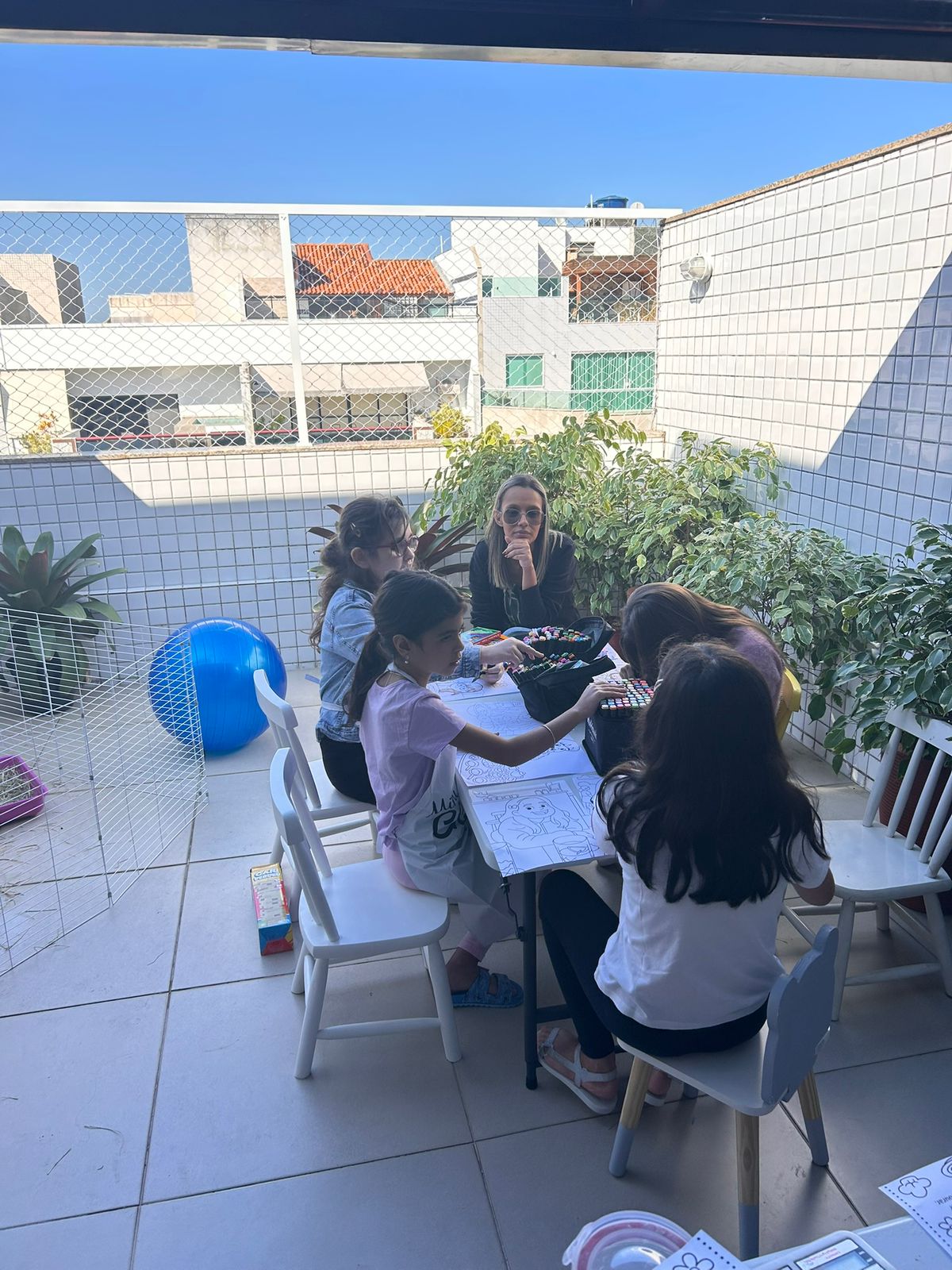 Crianças em oficina de desenho ao ar livre na cobertura do Espaço CoReS, acompanhadas por profissional.