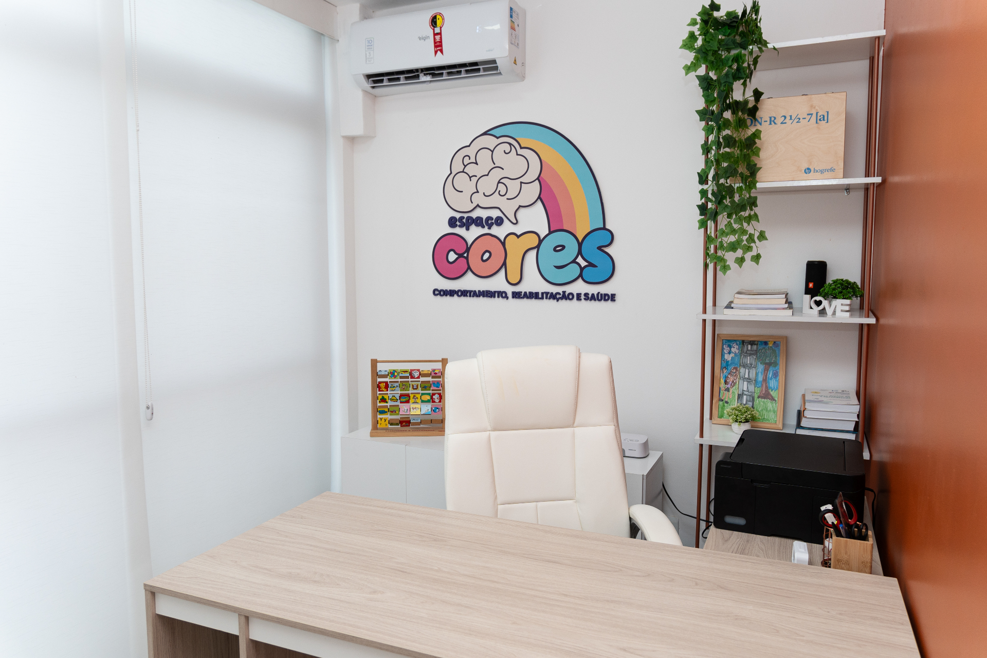 Consultório do Espaço CoReS com logo na parede, cadeira e materiais terapêuticos.